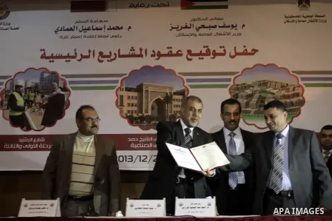 Palestinian Health Minister Mufid al-Mukhalalati (C), attends the signing ceremony of contracts of Qatari projects, in Gaza on Dec. 24, 2013. Photo by Mohammed Asad