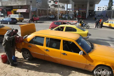 Palestinians wait to fill containers with fuel from a petrol station in Gaza city, on Jan. 6, 2014. Fuel stations suffering from acute fuel shortage due to Israel closure of Karem Shalom crossing for several days. Photo...