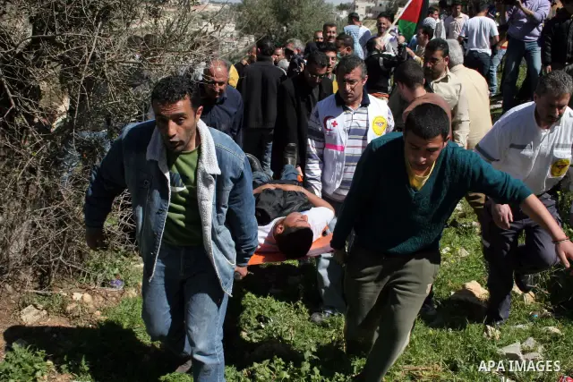 Palestinians carry an injured man during a demonstration against the construction of a section of the controversial Israeli barrier in the West Bank town of Beit Jala near Bethlehem March 7, 2010. Photo by Najeh Hashlamo...