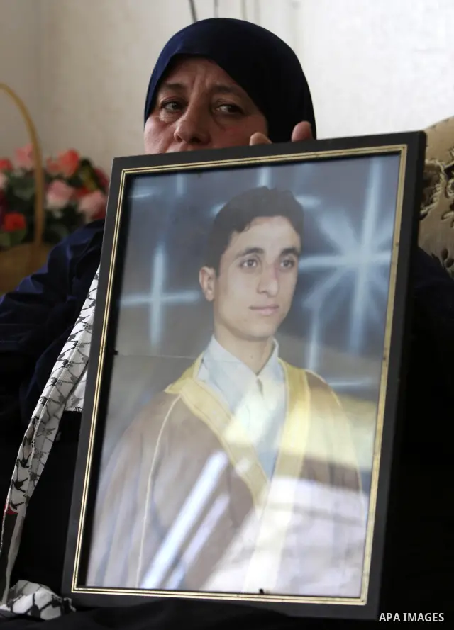 Mother of Palestinian prisoner Raed Abu Hamad, who died in an Israeli jail, holds his picture at her home in Al-Azariya on the outskirts of Jerusalem on April 17, 2010. Palestinians held rallies and vigils in an annual d...