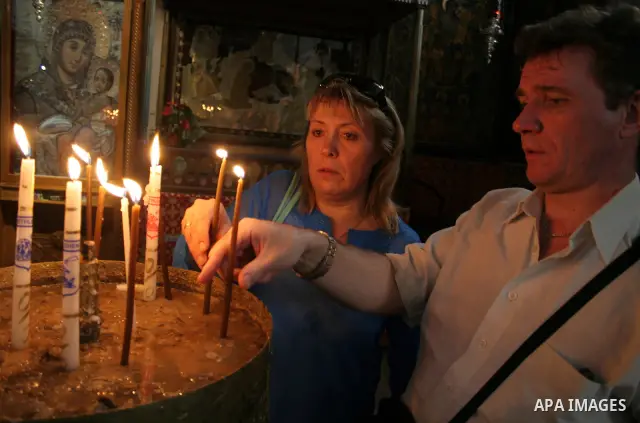 Worshippers light a candles in the Church of the Nativity, the traditionally accepted birhtplace of Jesus Christ, in the West Bank town of Bethlehem on April 22 2010, whose wall's are lined with paintings of the Virgin M...