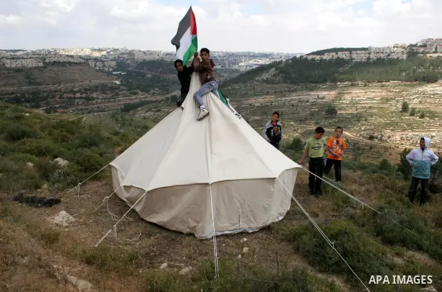 A Palestinian boy waves his national flag over a tent during a demonstration by Palestinians and foreign peace activists against Israel's controversial separation barrier in the West Bank village of Walajeh near the Pale...