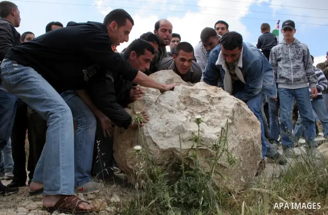 Palestinian demonstrators blocked the street with large stone during a demonstration against Israel's controversial separation barrier in the West Bank village of Walajeh near the Palestinian biblical town of Bethlehem o...