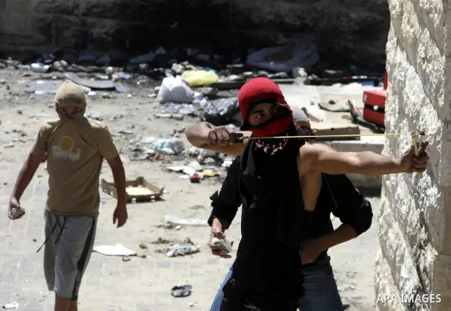 Palestinian youths throw stones at Israeli police during clashes in the Arab east Jerusalem neighbourhood of Silwan on April 25, 2010. Palestinian protesters clashed with Israeli police as dozens of ultra-nationalist Jew...