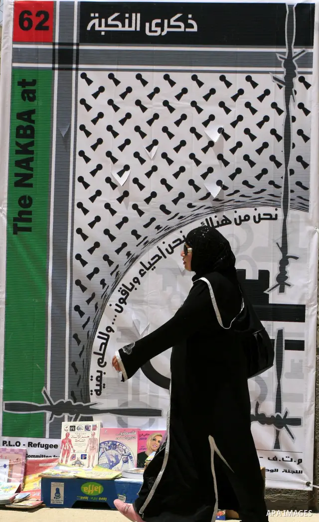 A Palestinian woman walks past a poster made for the 62nd anniversary of the "Nakba" (catastrophe) in the West Bank city of Ramallah on May 8, 2010. Nakba is what the Palestinians call the creation of the state of Israel...