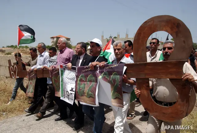 Palestinian demonstrators hold a giant key symbolising the keys to houses left by Palestinians in 1948 during a protest against the Israeli controversial separation barrier on the eve of Nakba Day in the West Bank villag...