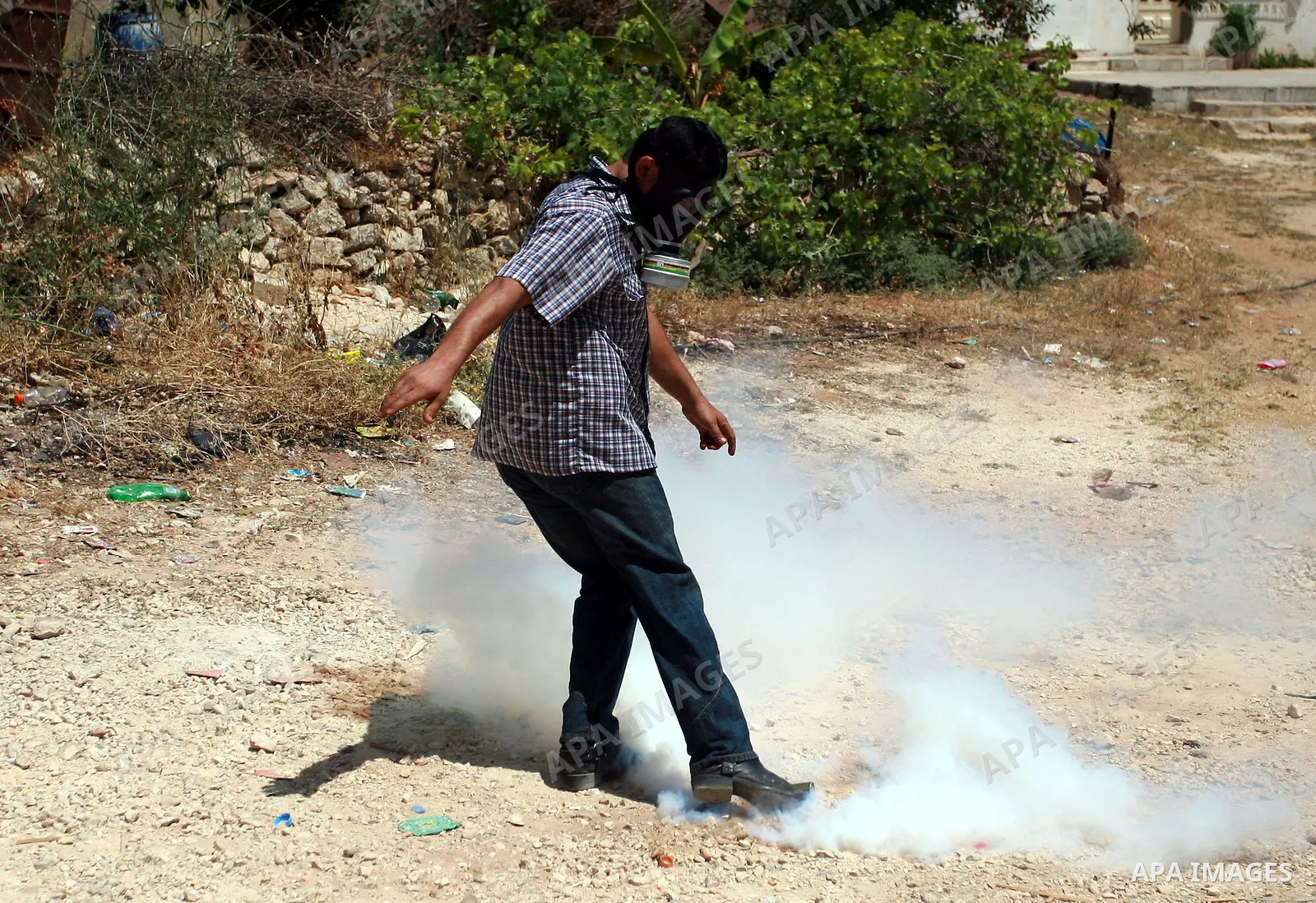 A Palestinian youth kicks a tear gas canister towards Israeli troops during clashes following a demonstration in the West Bank village of Nabi Saleh on May 21, 2010 against the expansion of the nearby Jewish settlement o...