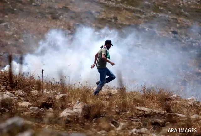 A Palestinian youth runs for cover from tear gas canister fired by Israeli soldier during clashes in the village of Iraq Burin near the West Bank city of Nablus on May 21, 2010. Photo by Wagdi Eshtayah