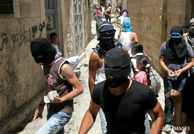 Masked Palestinian youths hurl stones at Israeli police during clashes in Jerusalem's old city, Monday, May 31, 2010. The clashes erupted during a protest against Israeli naval storming a flotilla of ships carrying aid a...