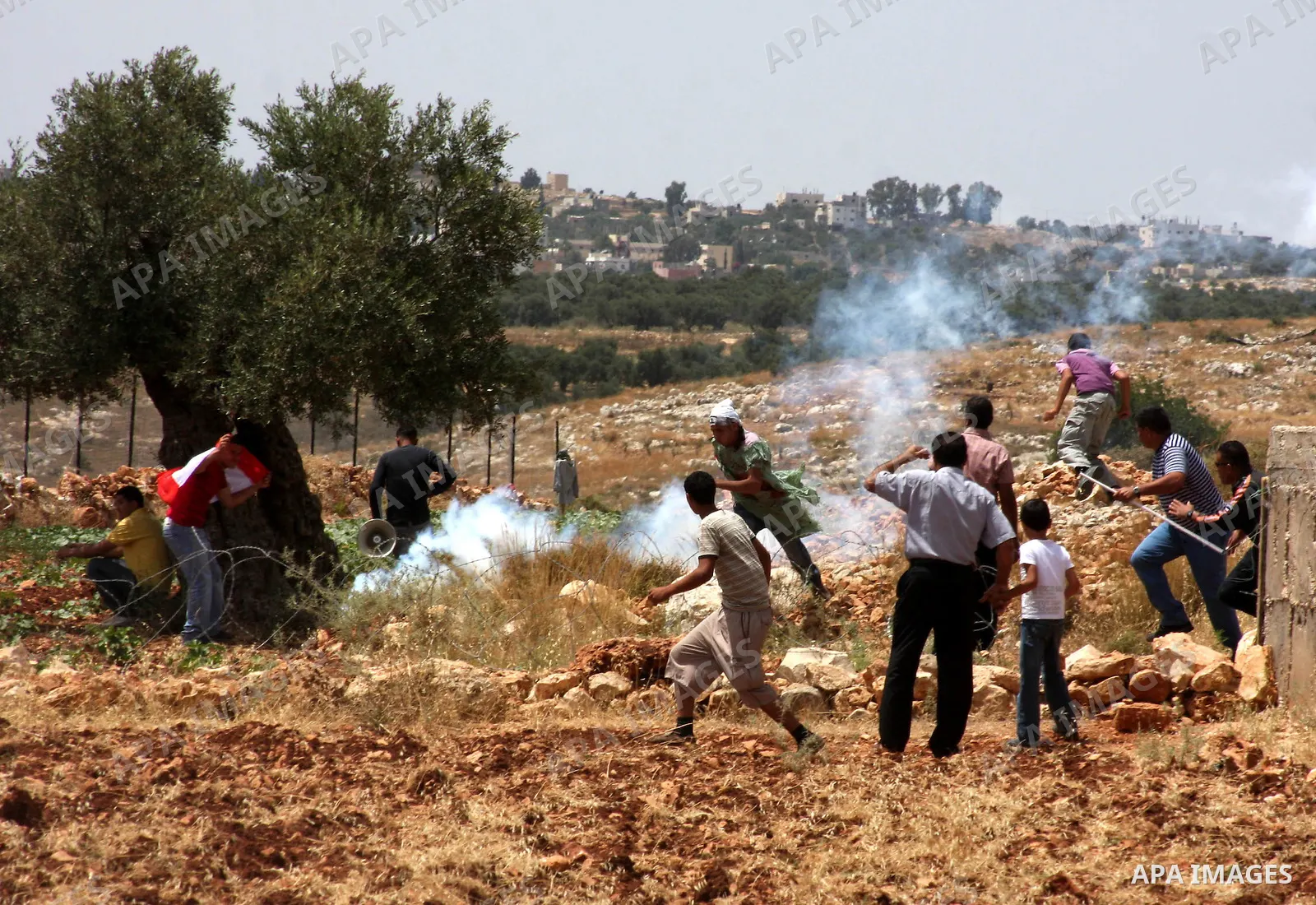 Palestinian, Israeli and foreign activists run from tear gas fired by Israeli soldiers during a protest against Israel's separation barrier outside the West Bank village of Bilin, near Ramallah, Friday on June 4, 2010. P...