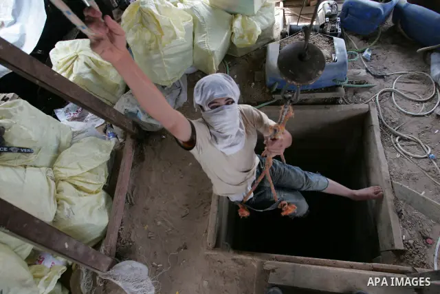 A Palestinian masked youth works inside a smuggling tunnel in Rafah, southern Gaza Strip on June 8, 2010. Egypt in its last stage of digging trenches and installing metal sheets underground along its border with Gaza in...