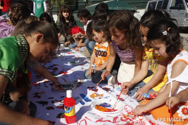 Members of the Temporary International observers draw with Palestinian children in the West Bank city of Hebron on June 9, 2010. Israel is considering the option of not extending the mandate of the TIPH multi-national mi...