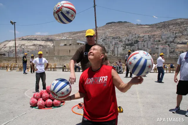 American basketball handler, Tanya Crevier shows a Palestinian children how to play a basketball in the West Bank city of Nablus,Thursday, June 10, 2010. Crevier, a former professional basketball player in the US, is on...