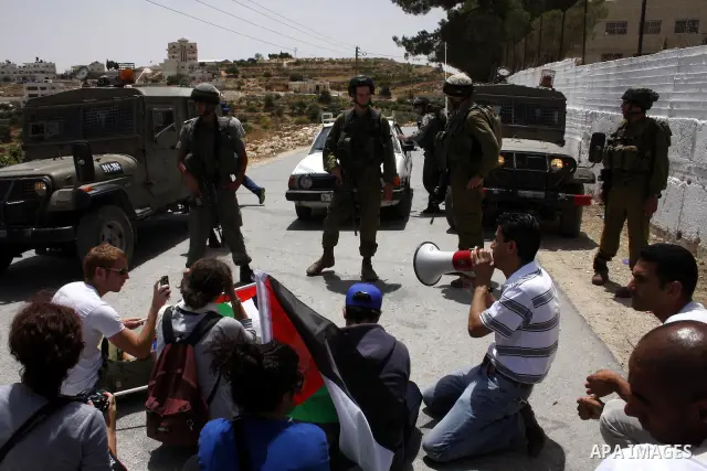 Palestinian, Israeli and foreign peace activists take part in a demonstration against Israel's controversial separation barrier in the West Bank village of Maasarah, near the biblical town of Bethlehem, on June 11, 2010....