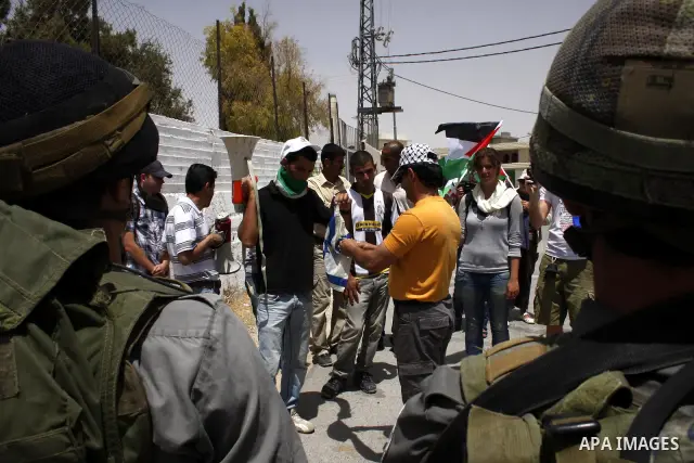 Palestinian, Israeli and foreign peace activists take part in a demonstration against Israel's controversial separation barrier in the West Bank village of Maasarah, near the biblical town of Bethlehem, on June 11, 2010....