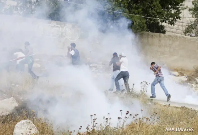 Israeli soldiers fire tear gas canister to disperse Palestinian protesters from the village of Bet In, north of Ramallah, as they hold up their national flag during protest against Israeli occupation on June 11, 2010 nea...