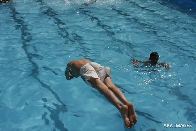 Palestinian youths jump into a swimming pool to cool off on a hot day, in the West Bank city of Hebron, where temperatures reached a high of 39 degrees Celsius (102 Fahrenheit) Tuesday, June 22, 2010. Photo by Mamoun Waz...