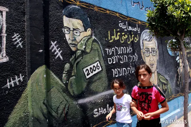 Palestinian girls walk in front of a mural depicting captured Israeli soldier Gilad Schalit on the main road in Jabaliya refugee camp, northern Gaza Strip on June 26, 2010. Four years since Schalit was captured by Hamas-...