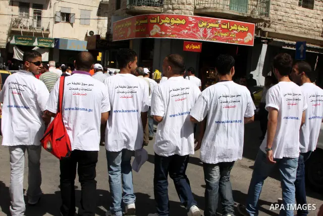 Palestinian volunteers attend a rally as they distribute a guidebook to boycott the settlements products in the West Bank city of Nablus, Monday June 28, 2010. The Palestinian authority launched a campaign of boycotting...