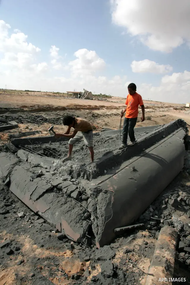 Palestinians try to break off gravel from a destroyed building at an abandoned airport that was hit by an Israeli air strike in the southern Gaza Strip July 1, 2010. The gravel will later be sold and used for new constru...