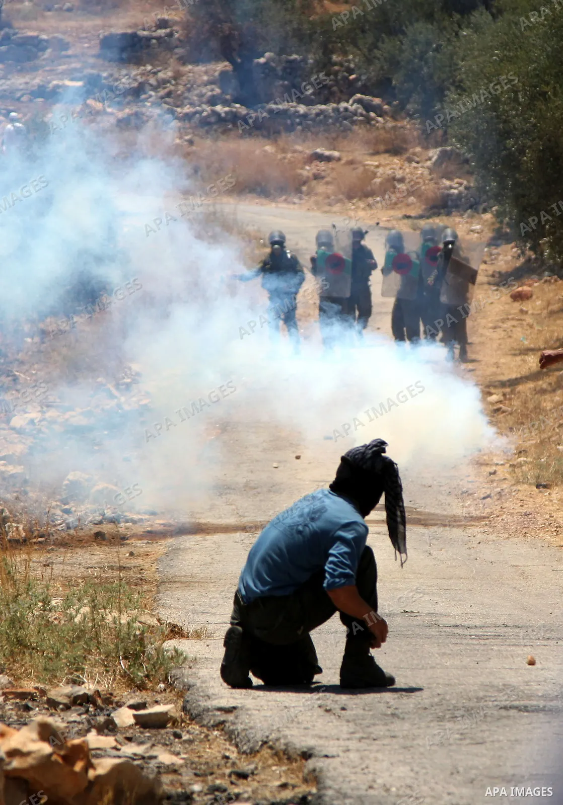 Palestinian protester takes cover from tear gas canisters fired by Israeli soldiers during a demonstration against Israel's separation barrier in the West Bank village of Bilin near Ramallah, Friday, July 2, 2010. Israel...
