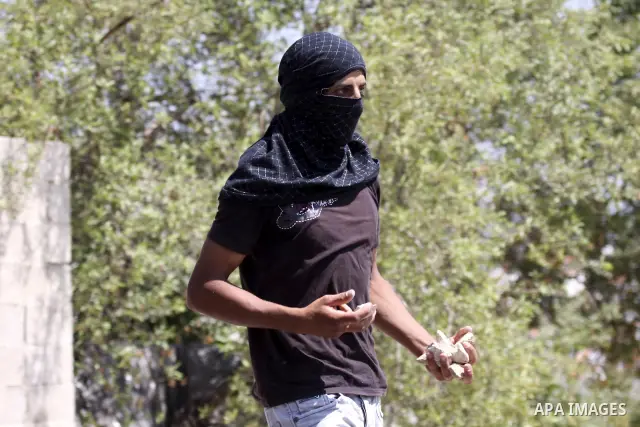 A Palestinian youth throws stones at Israeli soldiers during clashes following a protest in Nabi Saleh, near Ramallah, on July 2, 2010 against the expropriation of Palestinian land to expand the nearby Jewish settlement...