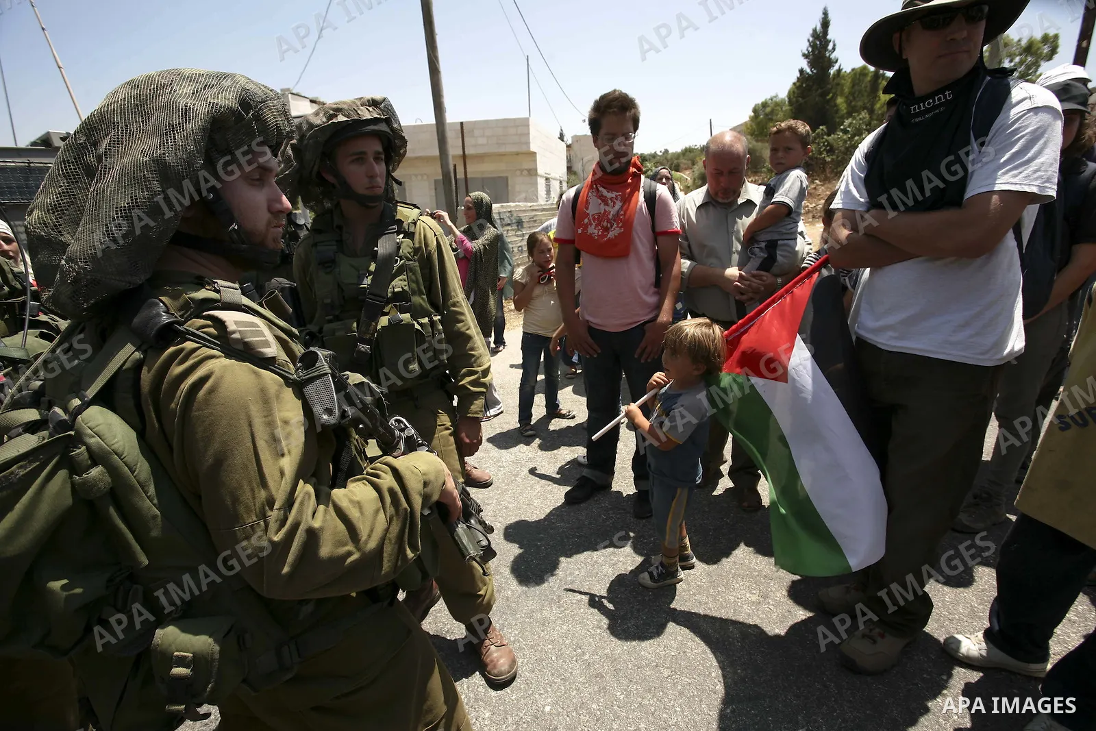 Israeli troops guard as Palestinian women and children shout slogans during a protest by locals, as well as foreign and leftwing Israeli peace activists, in Nabi Saleh, near Ramallah, on July 2, 2010 against the expropri...