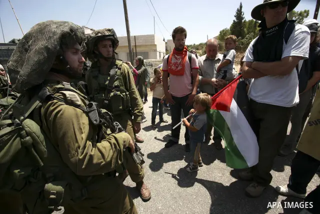 Israeli troops guard as Palestinian women and children shout slogans during a protest by locals, as well as foreign and leftwing Israeli peace activists, in Nabi Saleh, near Ramallah, on July 2, 2010 against the expropri...