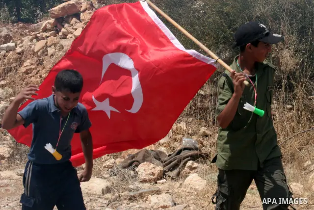 A Palestinian boy holds the Turkish flag during a demonstration by Palestinians and foreign peace activists, including Israeli leftwingers, in Beit Omar village, north of Hebron, on July 3, 2010 against the expropriation...