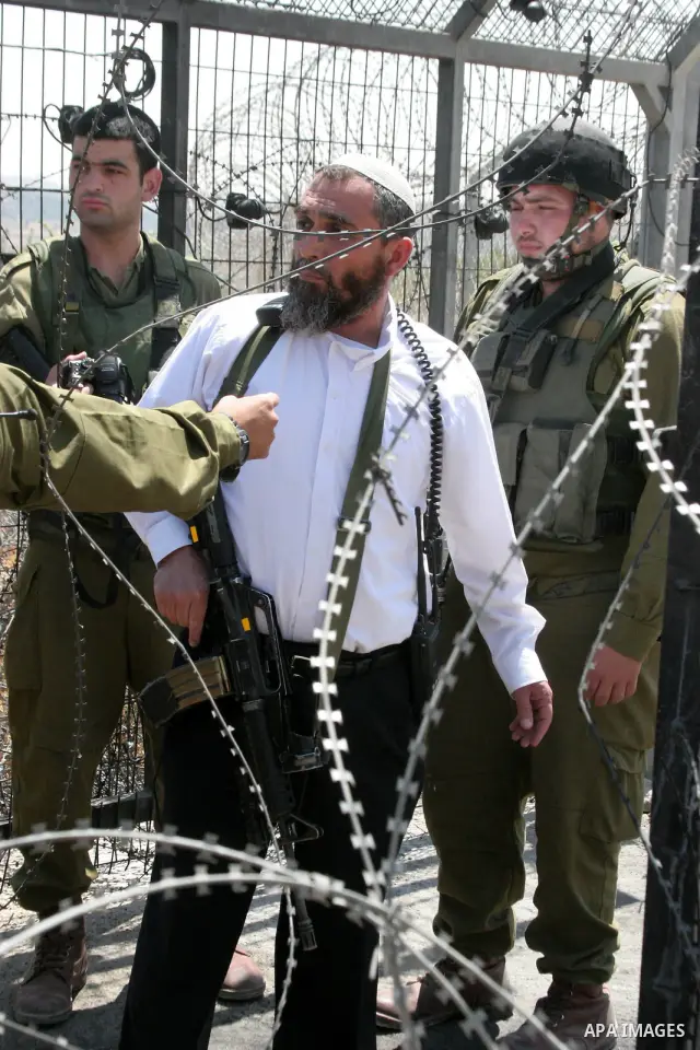 Israeli settler takes position during a demonstration by Palestinians and foreign peace activists, including Israeli leftwingers, in Beit Omar village, north of Hebron, on July 3, 2010 against the expropriation of Palest...
