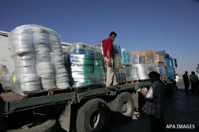 Palestinian men inspect the trucks loaded with goods and equipments after their arrival in the southern Gaza Strip through Kerem Shalom border crossing on July 6, 2010. Israel on Monday dropped its long-standing restrict...