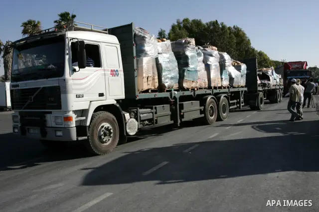 Palestinian men inspect the trucks loaded with goods and equipments after their arrival in the southern Gaza Strip through Kerem Shalom border crossing on July 6, 2010. Israel on Monday dropped its long-standing restrict...
