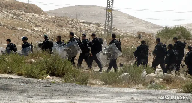 An Israeli border police officers guard as a Palestinian home is demolished in the east Jerusalem neighborhood of Isawiya, for being build without authorization, on 13 July 2010. On the background the separation barrier...