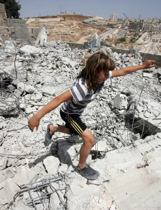 A Palestinian child walks on the remains of a Palestinian house that was demolished by the Israeli authorities in the East Jerusalem neighborhood of Isawiya, for being build without authorization, on 13 July 2010. On the...