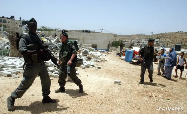 An Israeli border police officers guard as a Palestinian home is demolished in the east Jerusalem neighborhood of Beit Hanina, Tuesday, July 13, 2010. Israeli bulldozers destroyed at least two homes and two other buildin...
