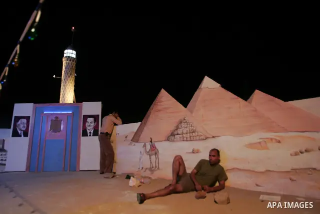 A Palestinian man sit on one side of the roof of his house in the southern Gaza Strip town of Rafah, near the border with Egypt, on July 14, 2010, where he has recreated Egypt's landmark sites with mural paintings and sc...