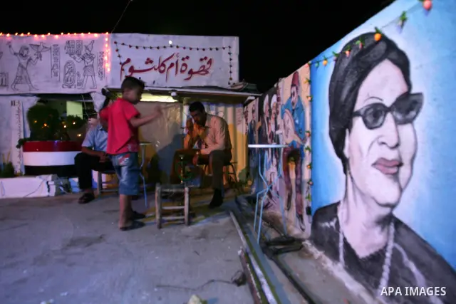 A Palestinian man sit on one side of the roof of his house in the southern Gaza Strip town of Rafah, near the border with Egypt, on July 14, 2010, where he has recreated Egypt's landmark sites with mural paintings and sc...