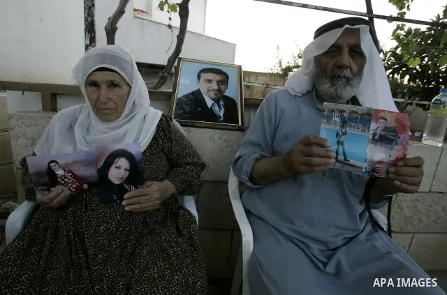 An elderly Palestinian couple display pictures of their two daughters, who are militants for the Popular Front for the Liberation of Palestine (PFLP), after they were arrested along with eleven people during raids by the...