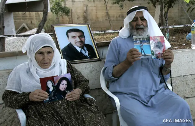 An elderly Palestinian couple display pictures of their two daughters, who are militants for the Popular Front for the Liberation of Palestine (PFLP), after they were arrested along with eleven people during raids by the...