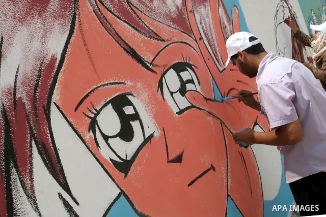 A Palestinian man paints part of a wall painting made to support attempts to break the Israeli naval blockade on Gaza, at the sea port in Gaza City, Thursday, July 15, 2010. A Libyan ship carrying aid for the impoverishe...