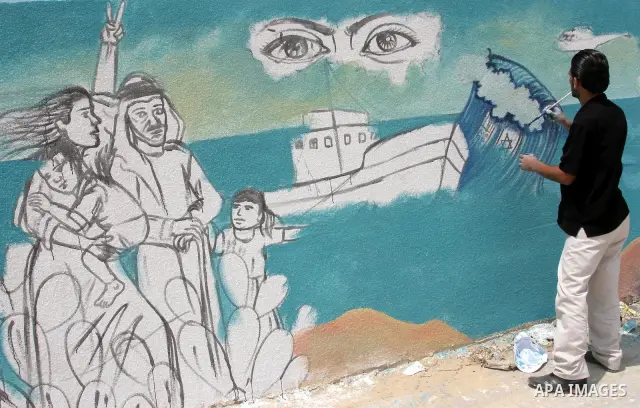 A Palestinian man paints part of a wall painting made to support attempts to break the Israeli naval blockade on Gaza, at the sea port in Gaza City, Thursday, July 15, 2010. A Libyan ship carrying aid for the impoverishe...