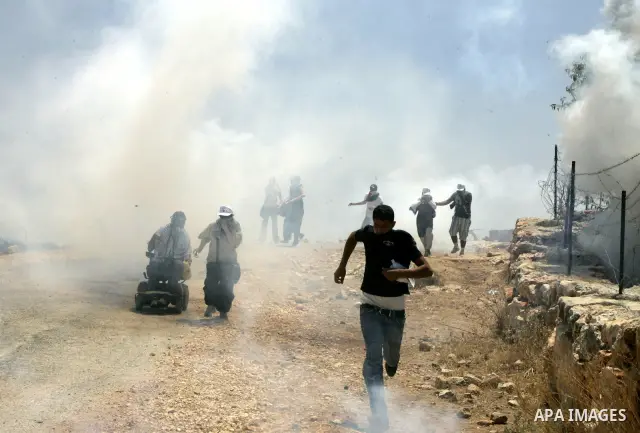 Palestinian protesters run for cover from tear gas fired by Israeli soldiers during a protest by Palestinian, Israeli and foreign activists against Israel's separation barrier outside the West Bank village of Bilin, near...