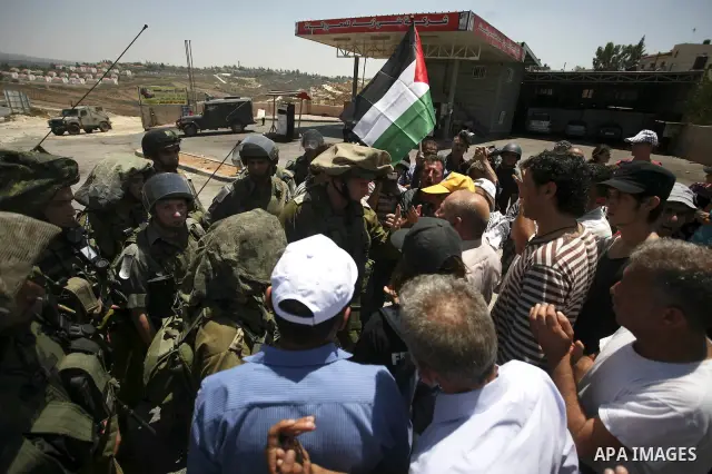Palestinian youths taunt an Israeli officer during a demonstration against the expansion of the nearby Jewish settlement of Halamish in the West Bank village of Nabi Saleh near Ramallah, Friday, July 16, 2010. Photo by E...