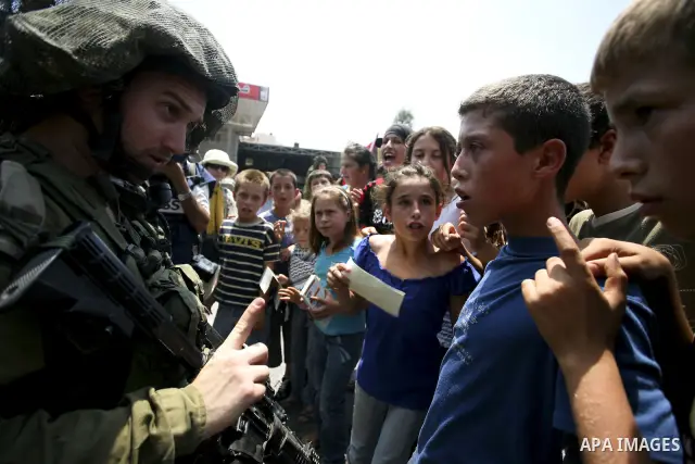 Palestinian youths taunt an Israeli officer during a demonstration against the expansion of the nearby Jewish settlement of Halamish in the West Bank village of Nabi Saleh near Ramallah, Friday, July 16, 2010. Photo by E...