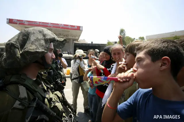 Palestinian youths taunt an Israeli officer during a demonstration against the expansion of the nearby Jewish settlement of Halamish in the West Bank village of Nabi Saleh near Ramallah, Friday, July 16, 2010. Photo by E...