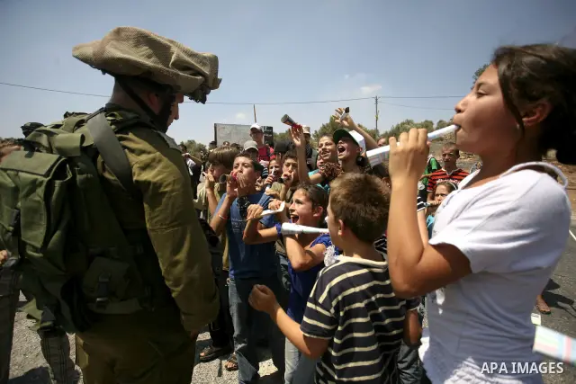 Palestinian youths taunt an Israeli officer during a demonstration against the expansion of the nearby Jewish settlement of Halamish in the West Bank village of Nabi Saleh near Ramallah, Friday, July 16, 2010. Photo by E...