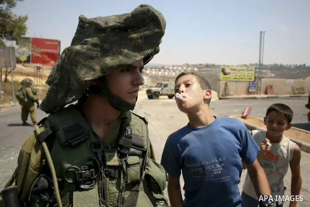 Palestinian youths taunt an Israeli officer during a demonstration against the expansion of the nearby Jewish settlement of Halamish in the West Bank village of Nabi Saleh near Ramallah, Friday, July 16, 2010. Photo by E...