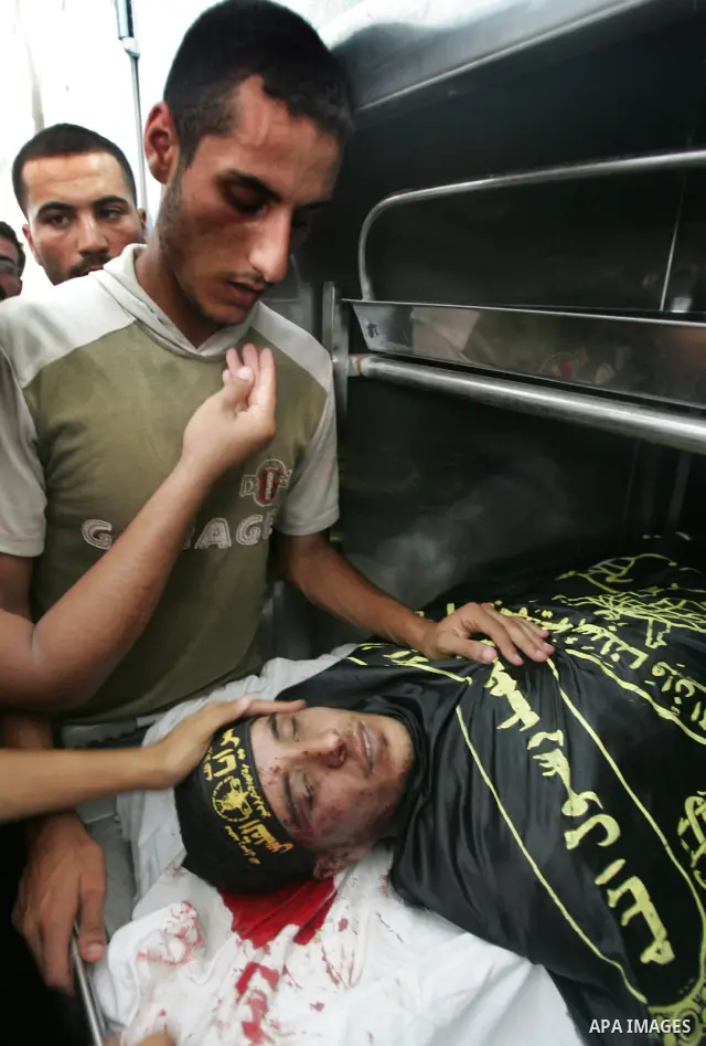 Palestinian mourners look at the body of Islamic Jihad militant Mohammed al-Kafarnah at a morgue in the town of Beit Hanoun in northern Gaza Strip July 21, 2010. Israeli shellfire killed al-Kafarnah and wounded seven peo...