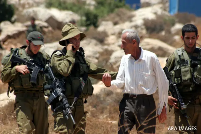 A Palestinian man argues with Israeli forces as he is taken away from his land which has been occupied by tents of armed Jewish ideological settlers (unseen) who are setting up a new outpost near the Israeli settlement o...