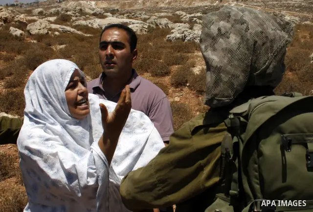 A Palestinian man argues with Israeli forces as he is taken away from his land which has been occupied by tents of armed Jewish ideological settlers (unseen) who are setting up a new outpost near the Israeli settlement o...